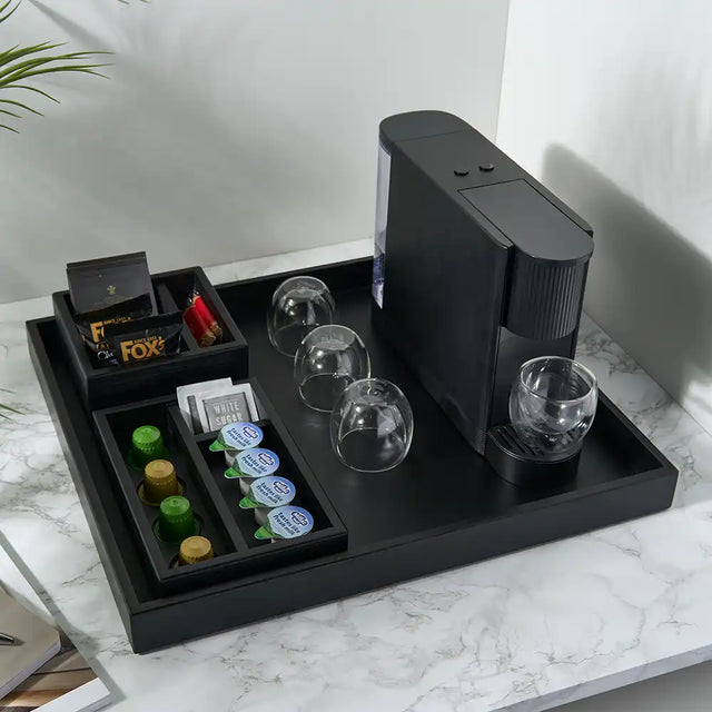 Black coffee maker with glasses and coffee pods on a marble surface