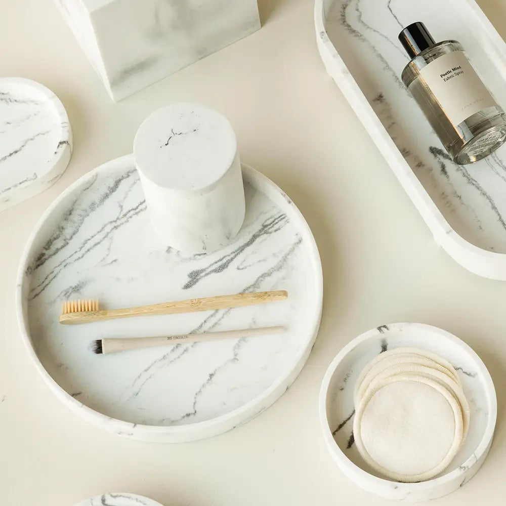 Marble-patterned amenity trays, a Toba jar and a brush on a light surface.