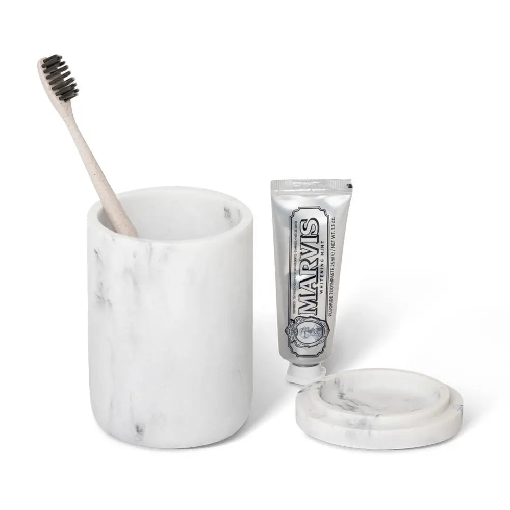 Marble toothbrush holder with a toothbrush and toothpaste on a white background