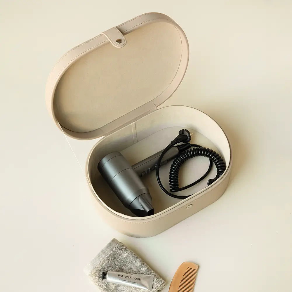 Portable hair dryer in a beige storage case on a light background