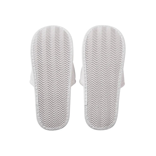 Pair of white slippers with textured sole on a white background