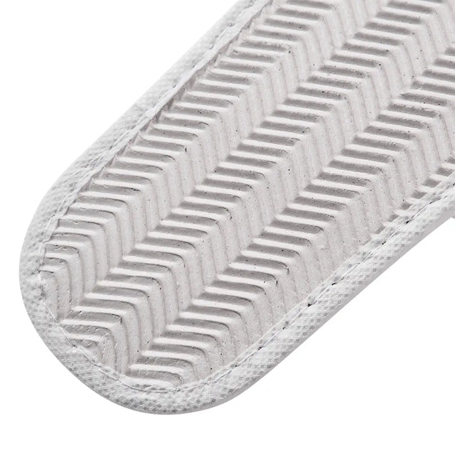 Close-up of a white slipper's sole with a zigzag pattern on a white background