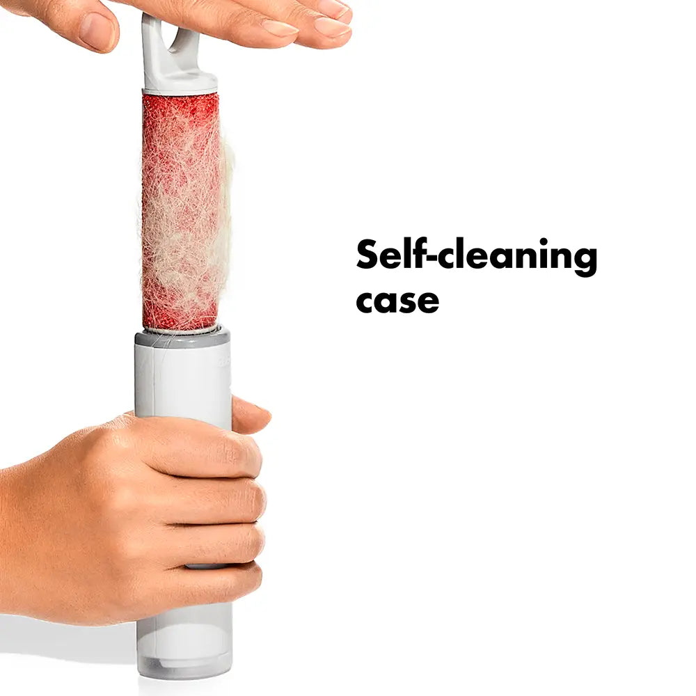 A handheld self-cleaning lint roller with a white handle and a red roller covered in white lint, held by hands against a white background with the text 'Self-cleaning case'.