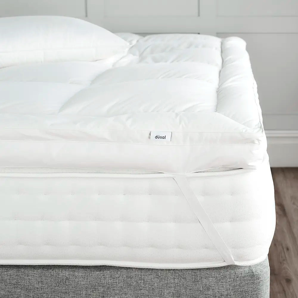 Dùsal Luxury Down Dual Layer Mattress Topper fitted on a bed with elasticated corner strap