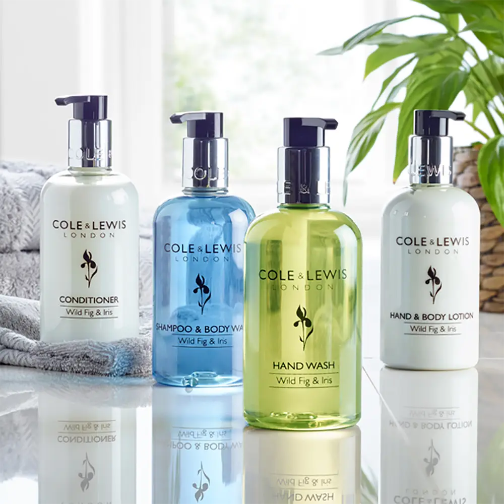 Cole & Lewis Wild Fig & Iris London skincare products on a reflective surface with a blurred background