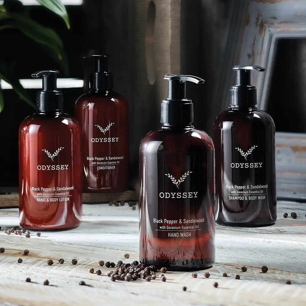 Odyssey skincare products including hand wash, body lotion, shampoo and hand lotion on a wooden surface.