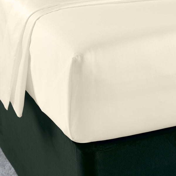 A percale flat sheet on a bed, with a small part flipped over, revealing the other side.