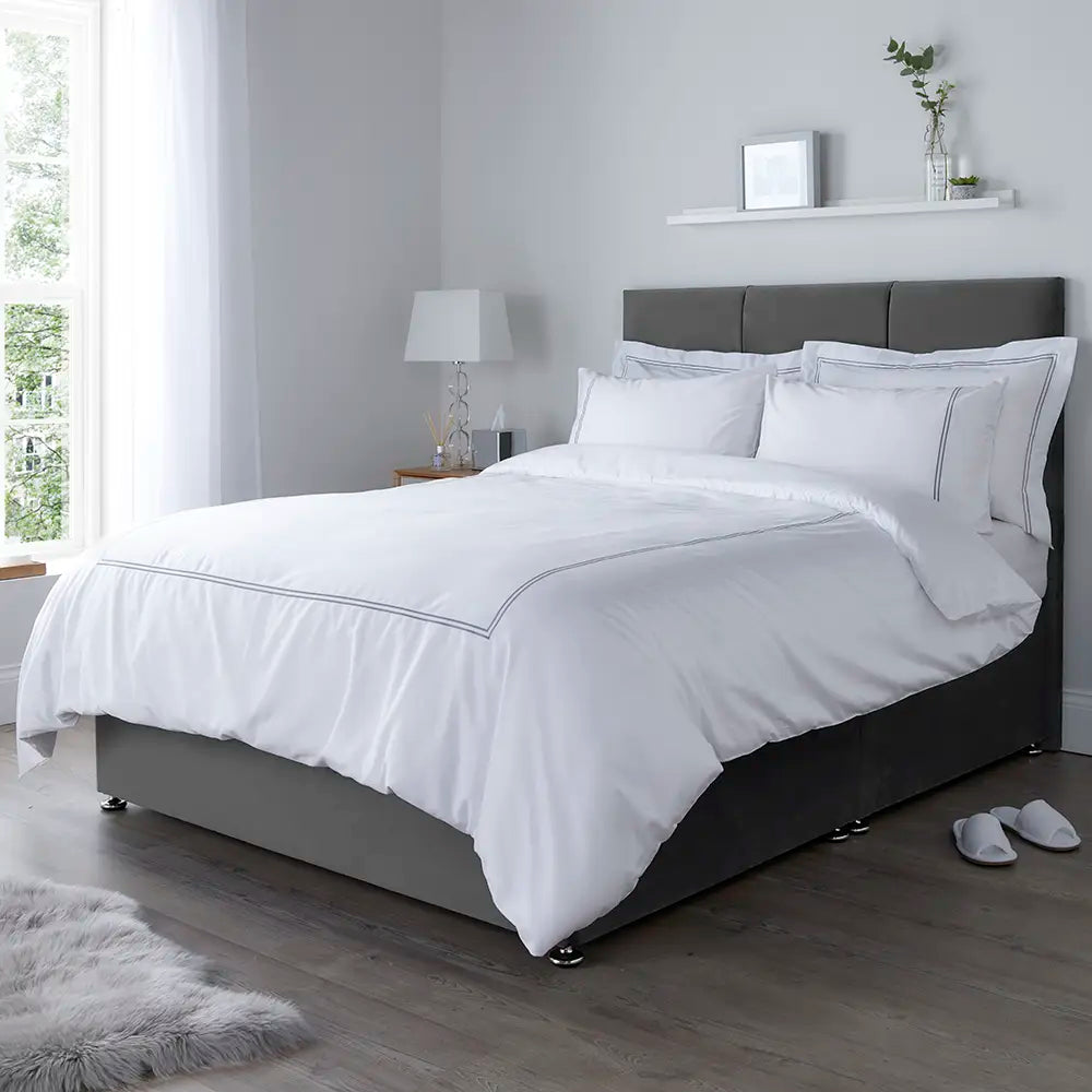 Corded Oxford bedsheets set on a gray bed frame in a bright bedroom.