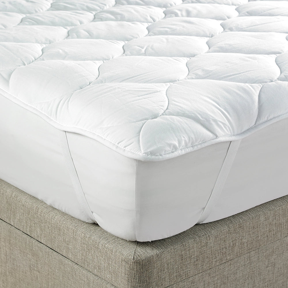 Close up of quilted mattress comforter on a bed showing the corner straps