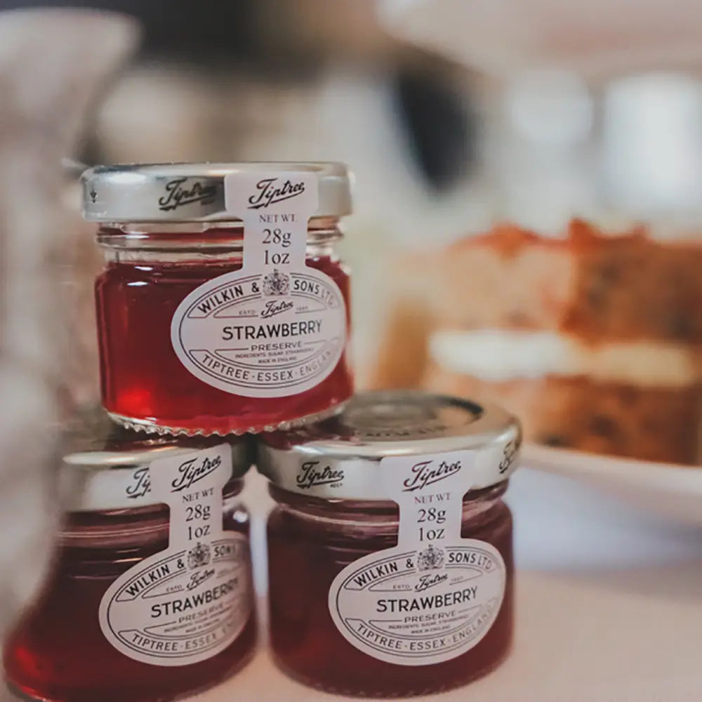 Three jars of tiptree strawberry jam preserve stacked on a blurred background
