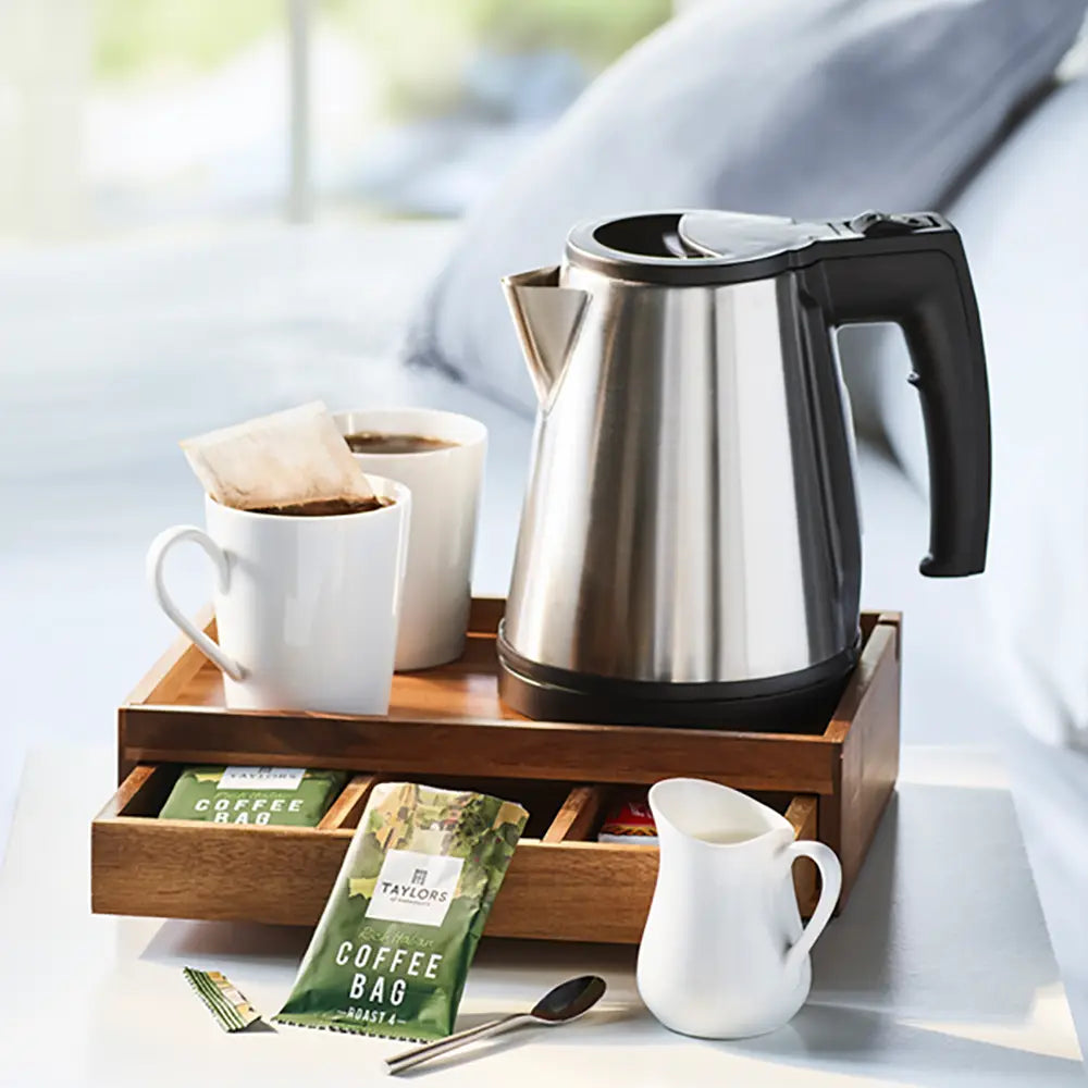 Stainless steel kettle on a wooden tray featuring Taylors coffee bags on a light background
