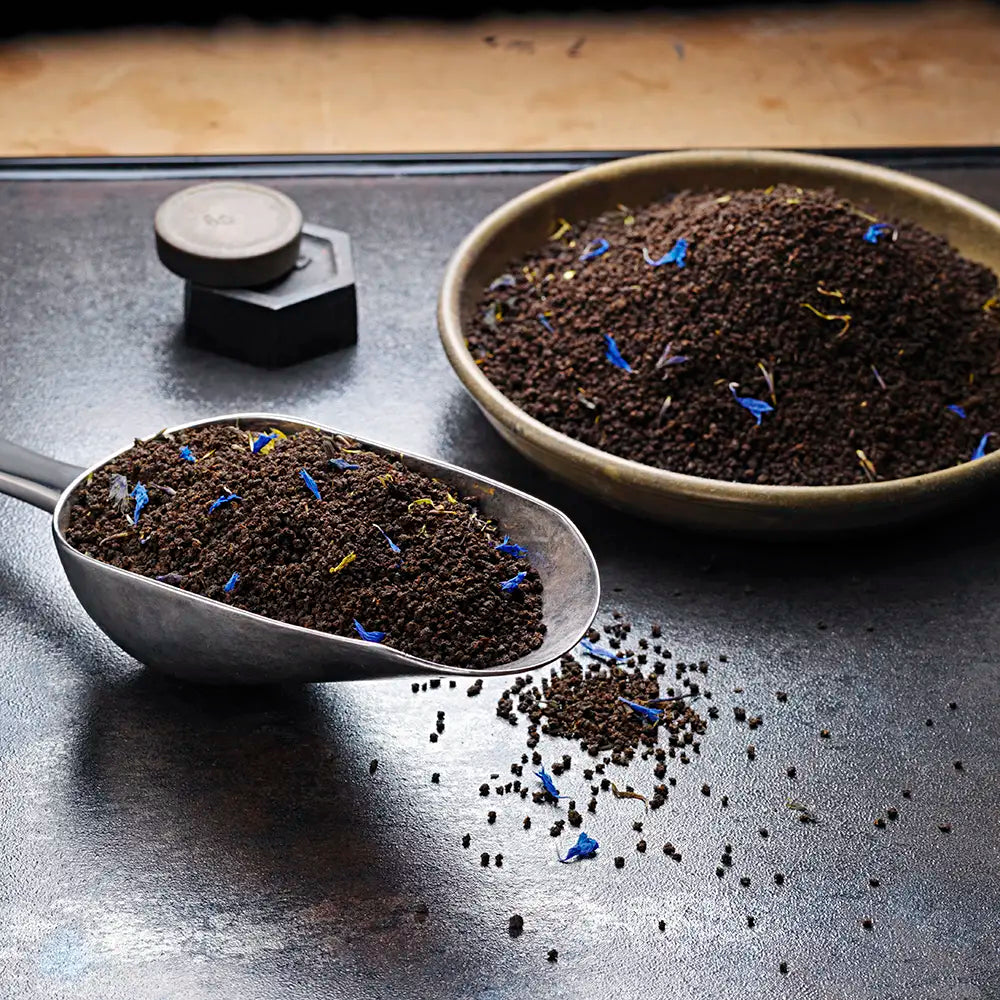 A bowl and scoop filled with earl grey tea leaves and flower petals from Birchall