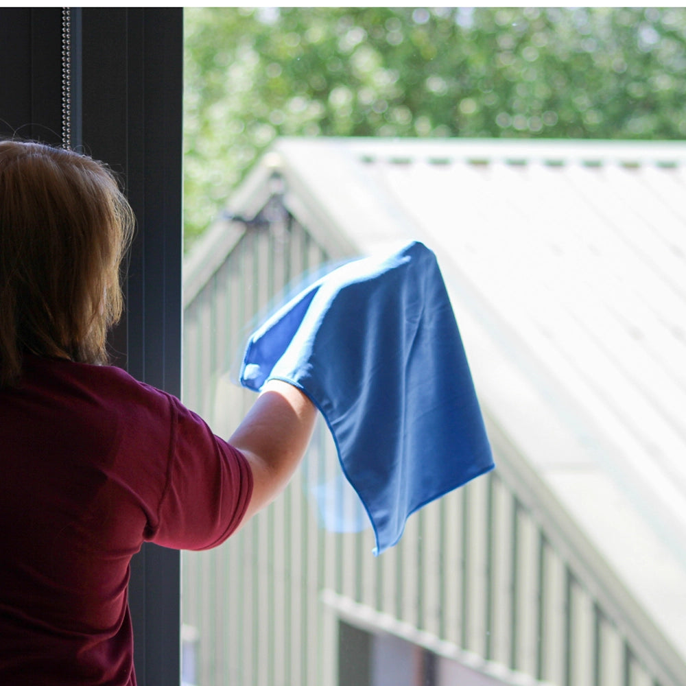 Cleaning a window with a blue glass cloth