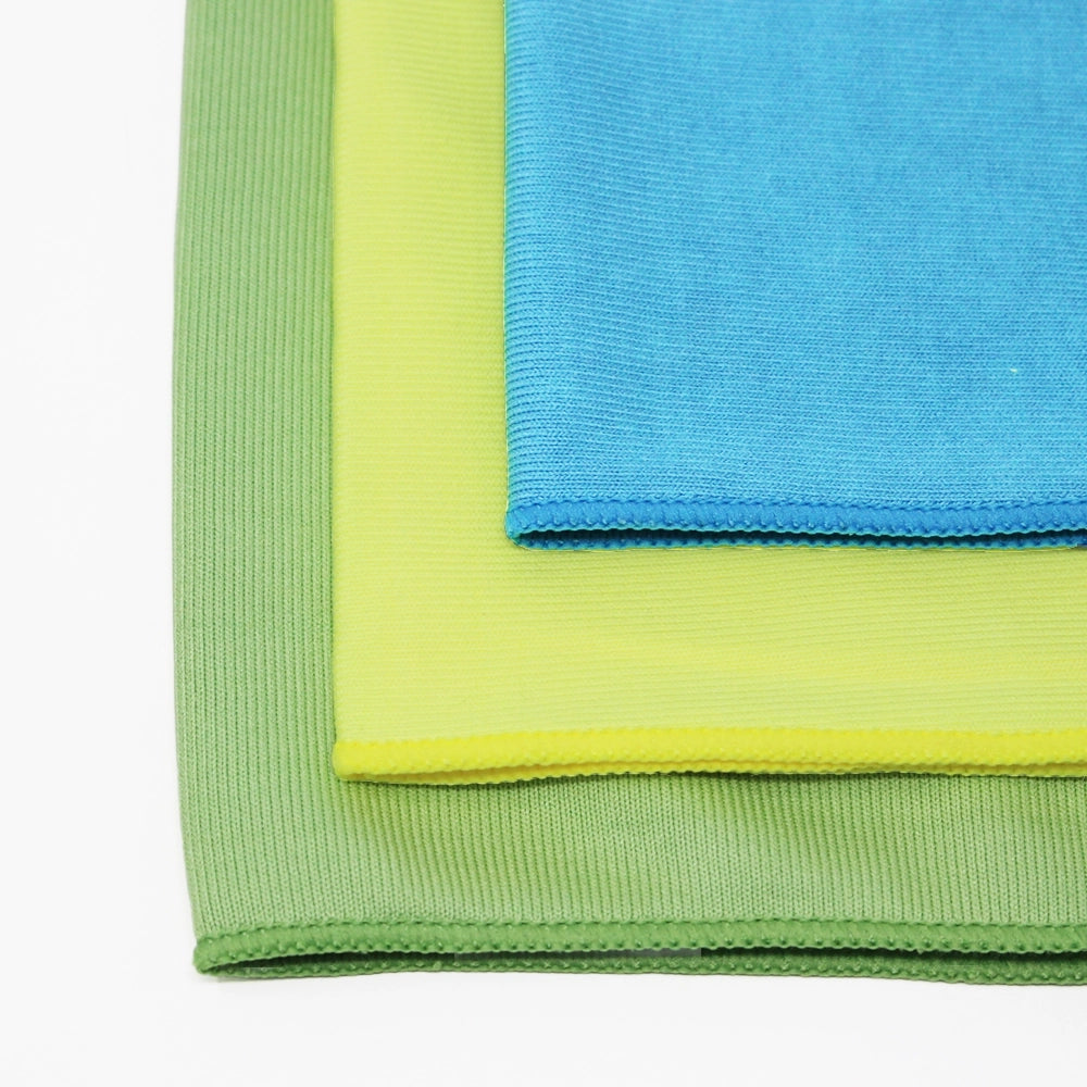 Three microfiber cloths, one green, one yellow and one blue, on a white background.