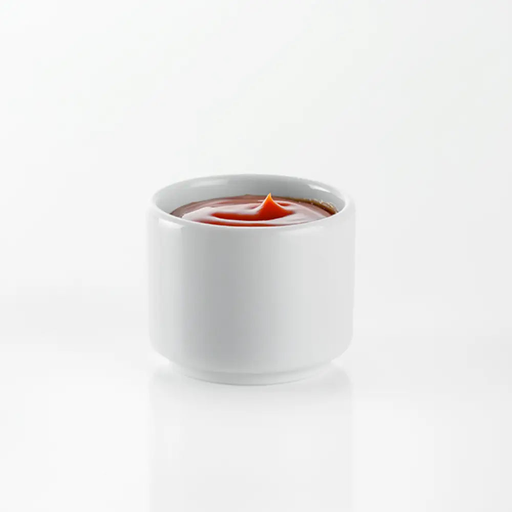 White ceramic cup with Ketchup inside on a white ground