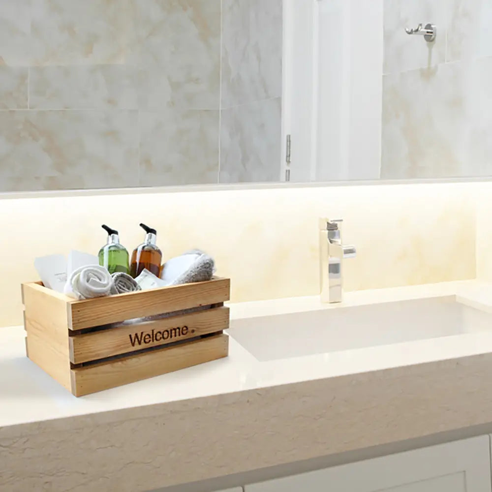 Wooden crate labeled 'Welcome' on a bathroom counter with bathroom toiletries