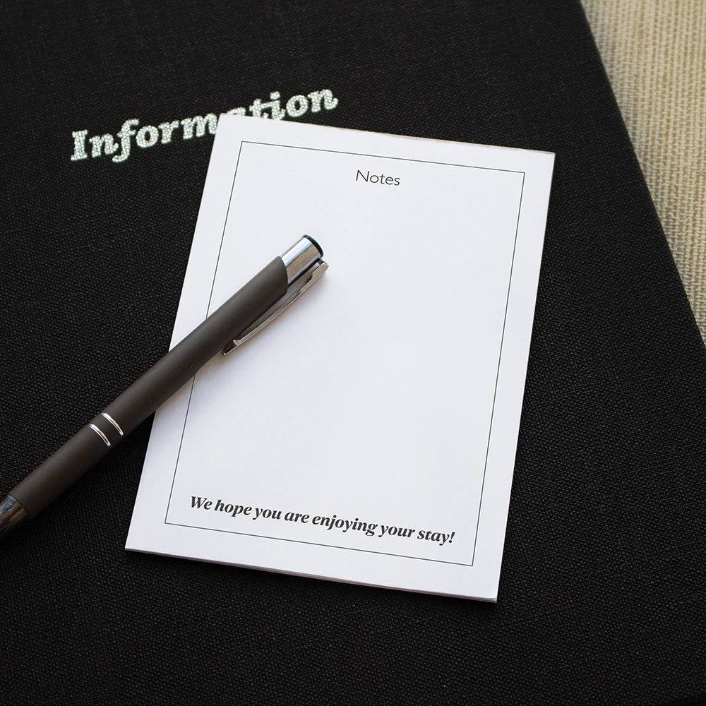 Message pad with a black pen sat on a black information folder
