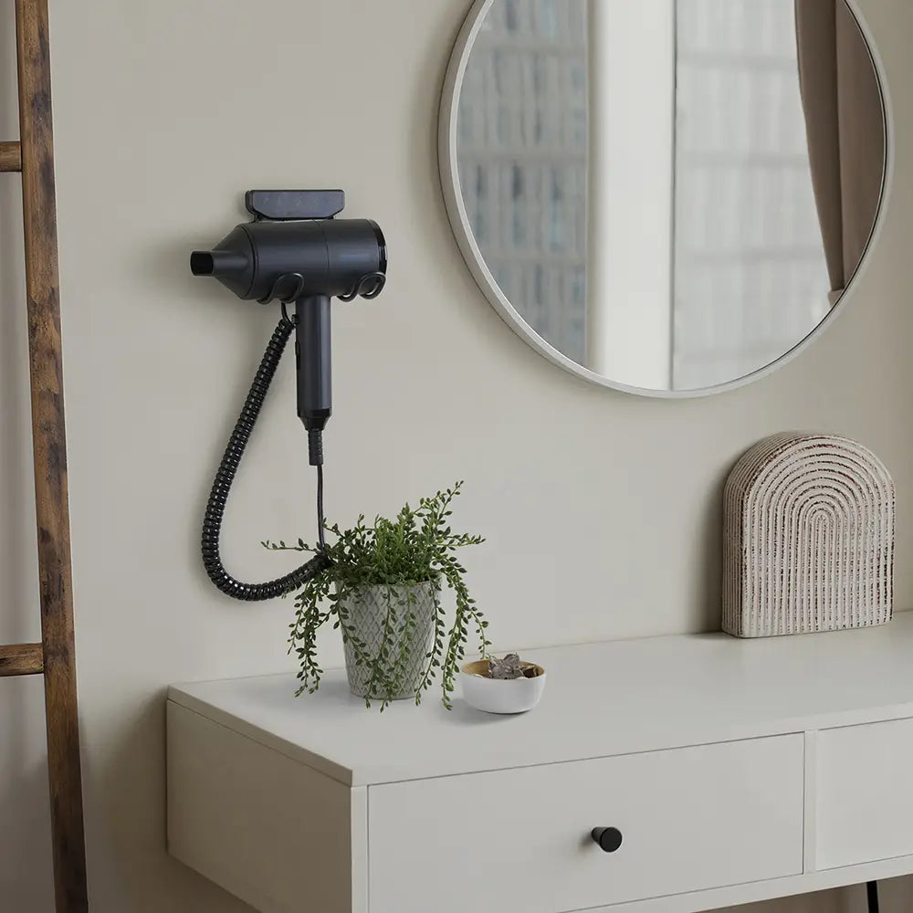 Back Hair dryer mounted on a wall above a dresser with decorative items.
