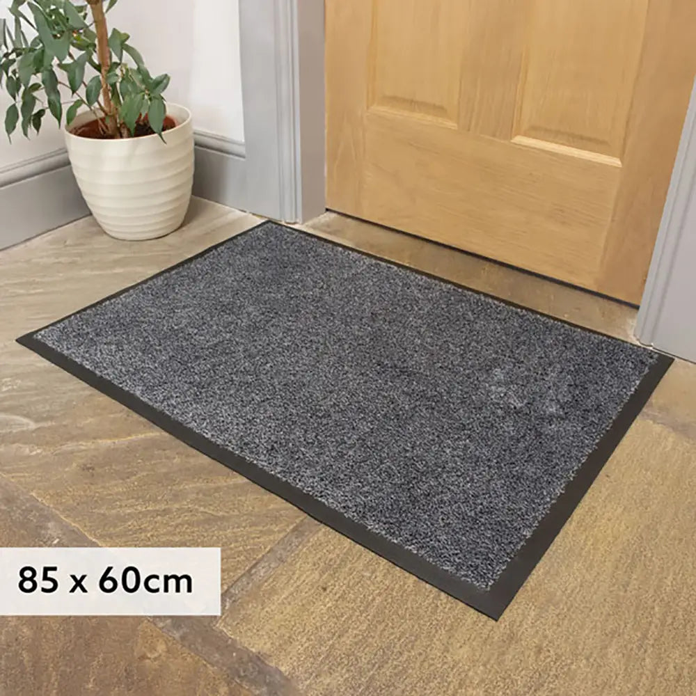 Gray doormat on a wooden floor with a plant nearby