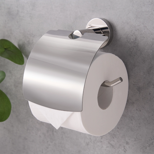 Chrome toilet paper holder with a roll of toilet paper on a grey wall.