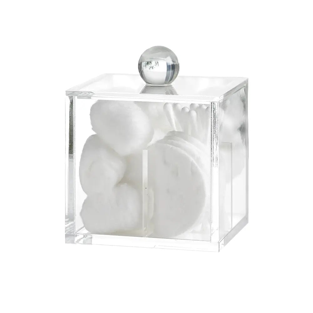 Clear acrylic cube container holding cotton wool balls, pads, cotton buds on a blurred natural background