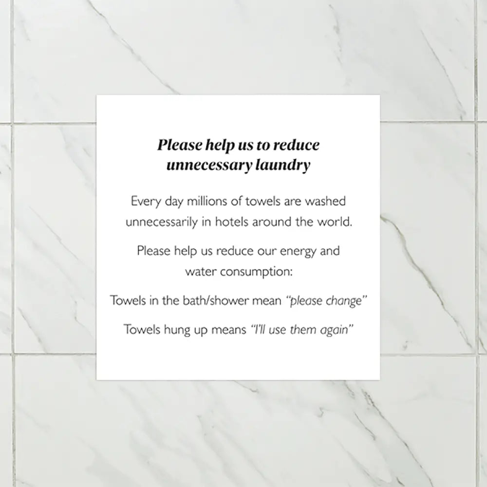 Sign on a tiled wall encouraging guests to reuse towels in hotels.