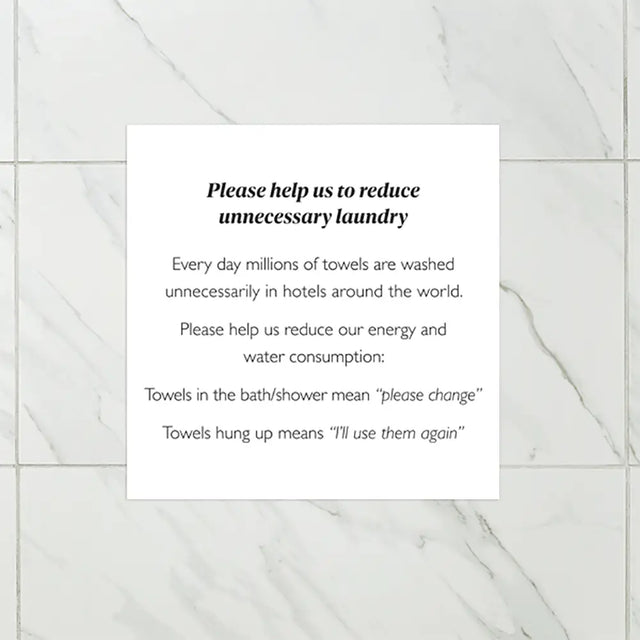 Sign on a tiled wall encouraging guests to reuse towels in hotels.