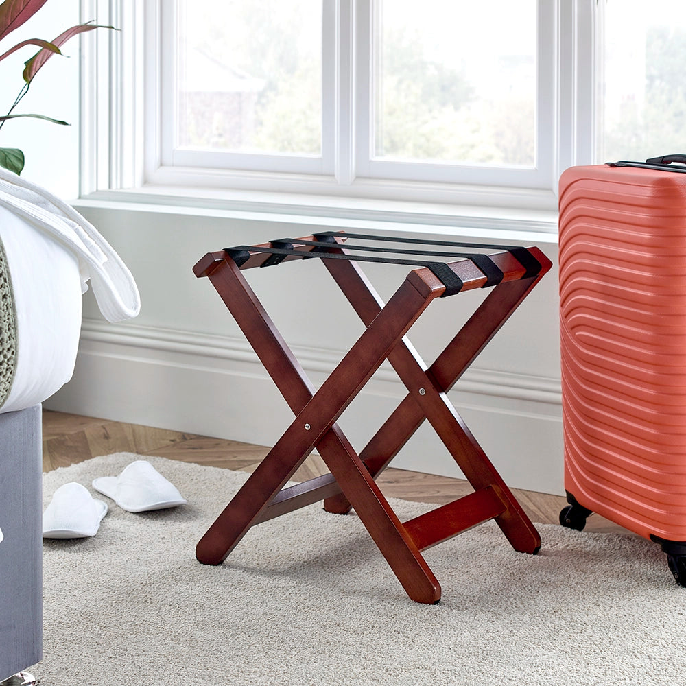Dark wood luggage stand with suitcase at the side in a bedroom setting