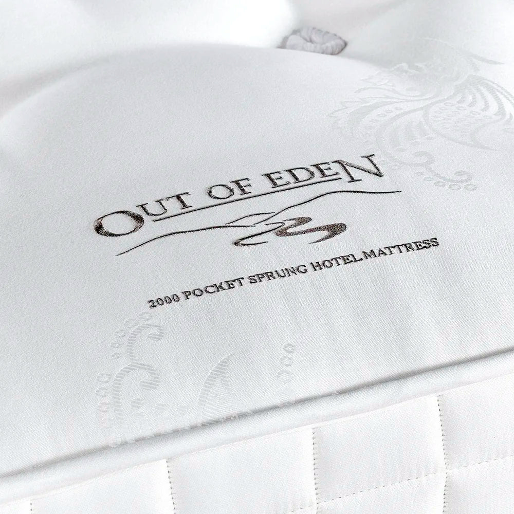 Close-up of the top corner of a white luxury pocket sprung hotel mattress with the brand 'Out of Eden' visible on the fabric.