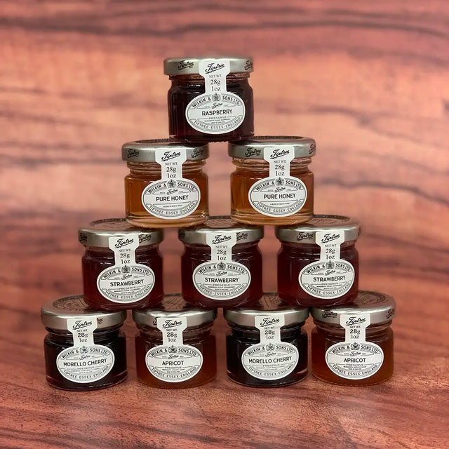Pyramid of jam jars with visible brand labels on a wooden surface