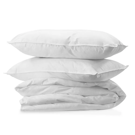 Stack of white pillows and a folded white duvet on a white background