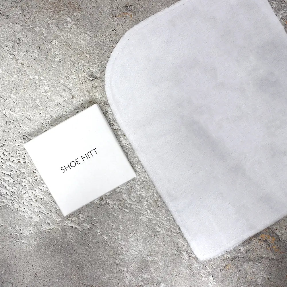 White shoe mitt and packaging on a gray concrete surface