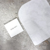 White shoe mitt and packaging on a gray concrete surface