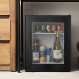 Small black refrigerator with drinks inside, next to wooden cabinets.