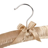 Gold satin fabric rolled up on a silver hanger with a bow against a white background