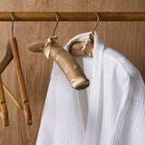 White bathrobe on a gold hanger with wooden hangers against a wooden background