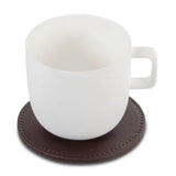 White ceramic mug on a brown leather-effect coaster with a white background