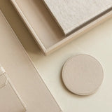 Round beige coaster on a matching surface with a neutral background