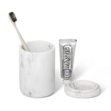 Marble toothbrush holder with a toothbrush and toothpaste on a white background