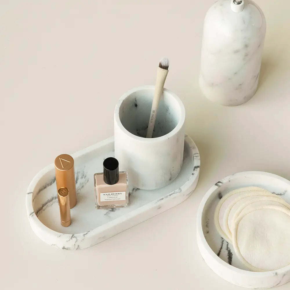 Marble-patterned tray with a small Toba jar and a brush on a light pink background