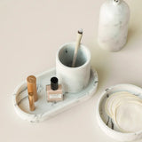 Marble-patterned tray with a small Toba jar and a brush on a light pink background