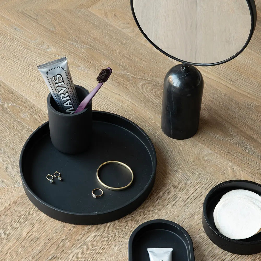 Black tray with Toba Jar, personal care items on a wooden surface