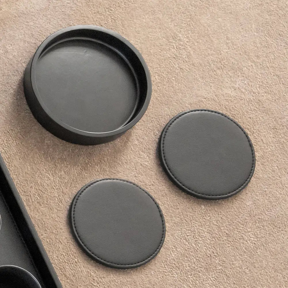 Two round black coasters on a beige surface