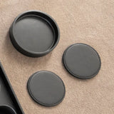 Two round black coasters on a beige surface