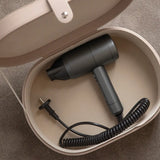 Black hair dryer with coiled cord inside a beige storage case