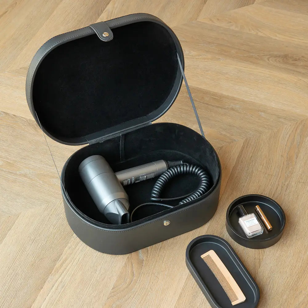 Black storage case with hair dryer, comb, and other items on a wooden surface