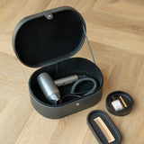 Black storage case with hair dryer, comb, and other items on a wooden surface