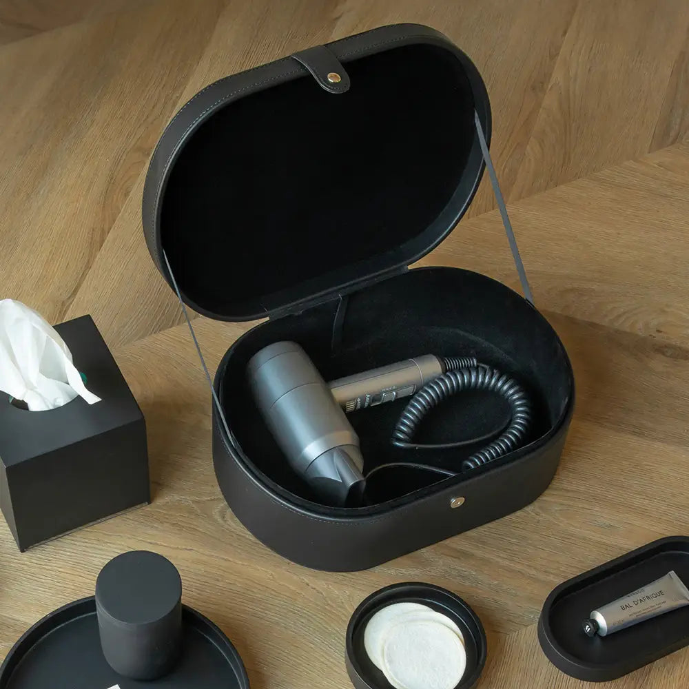 Black travel hair dryer case with hair dryer inside on a wooden surface