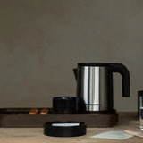 Stainless steel electric kettle on a brown tray with a minimal background