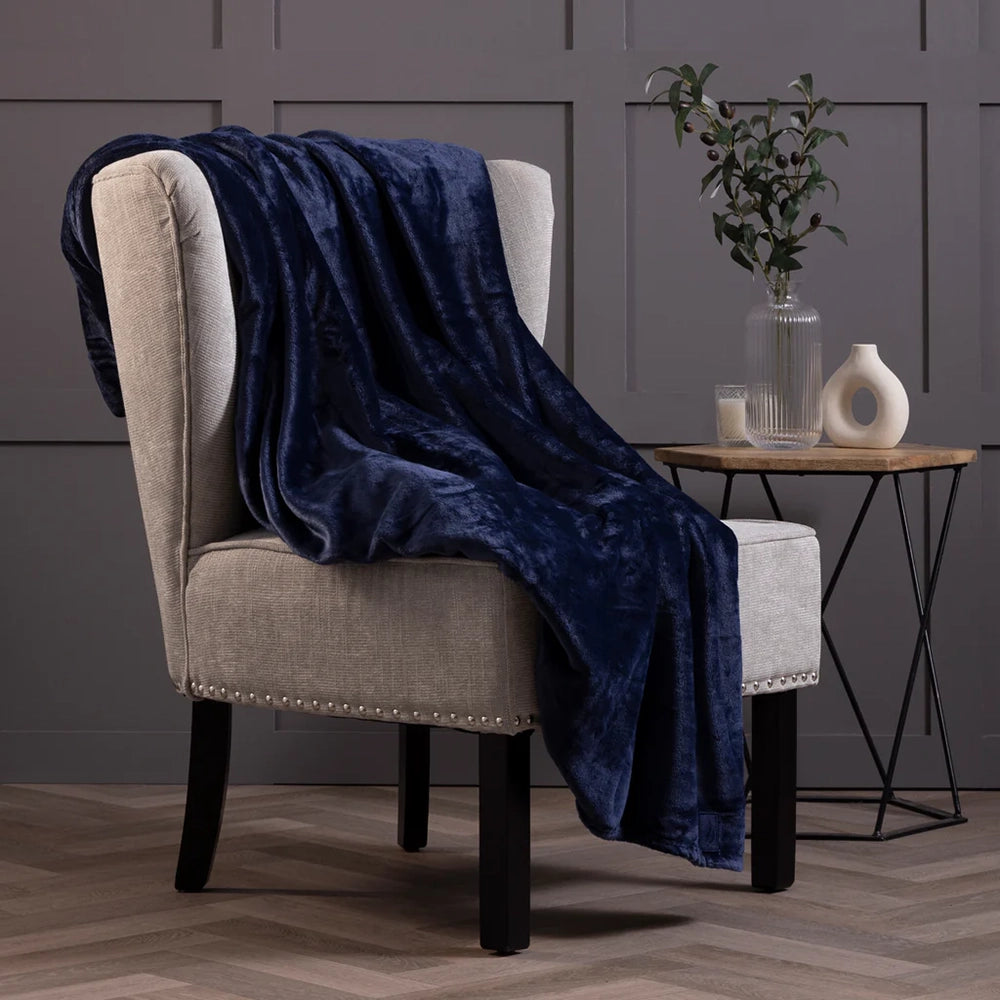 Blue blanket draped over a grey armchair with a side table in the background